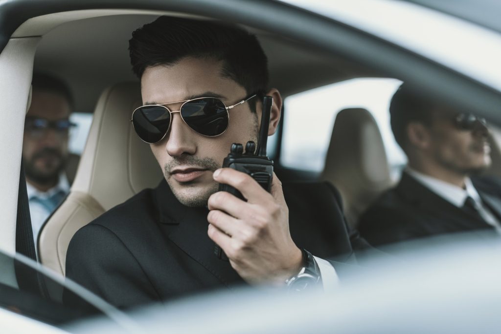 bodyguard in sunglasses talking by portable radio